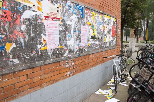 脏乱的广告牌，被撕下的散落一地的广告单，横停的自行车 李晔