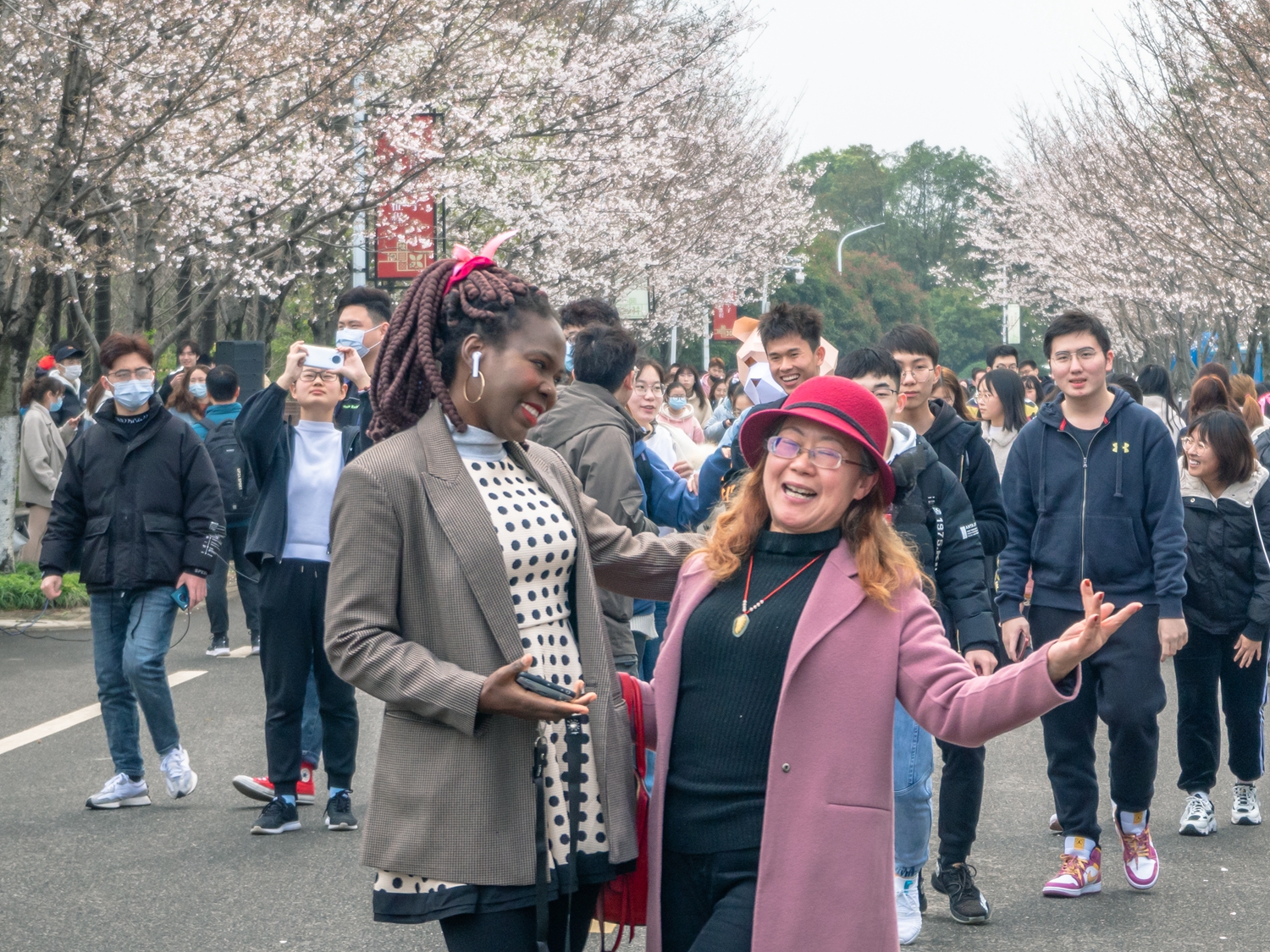 老师与留学生同学在樱花树下拍照（学通社记者 邓颖骏 摄）