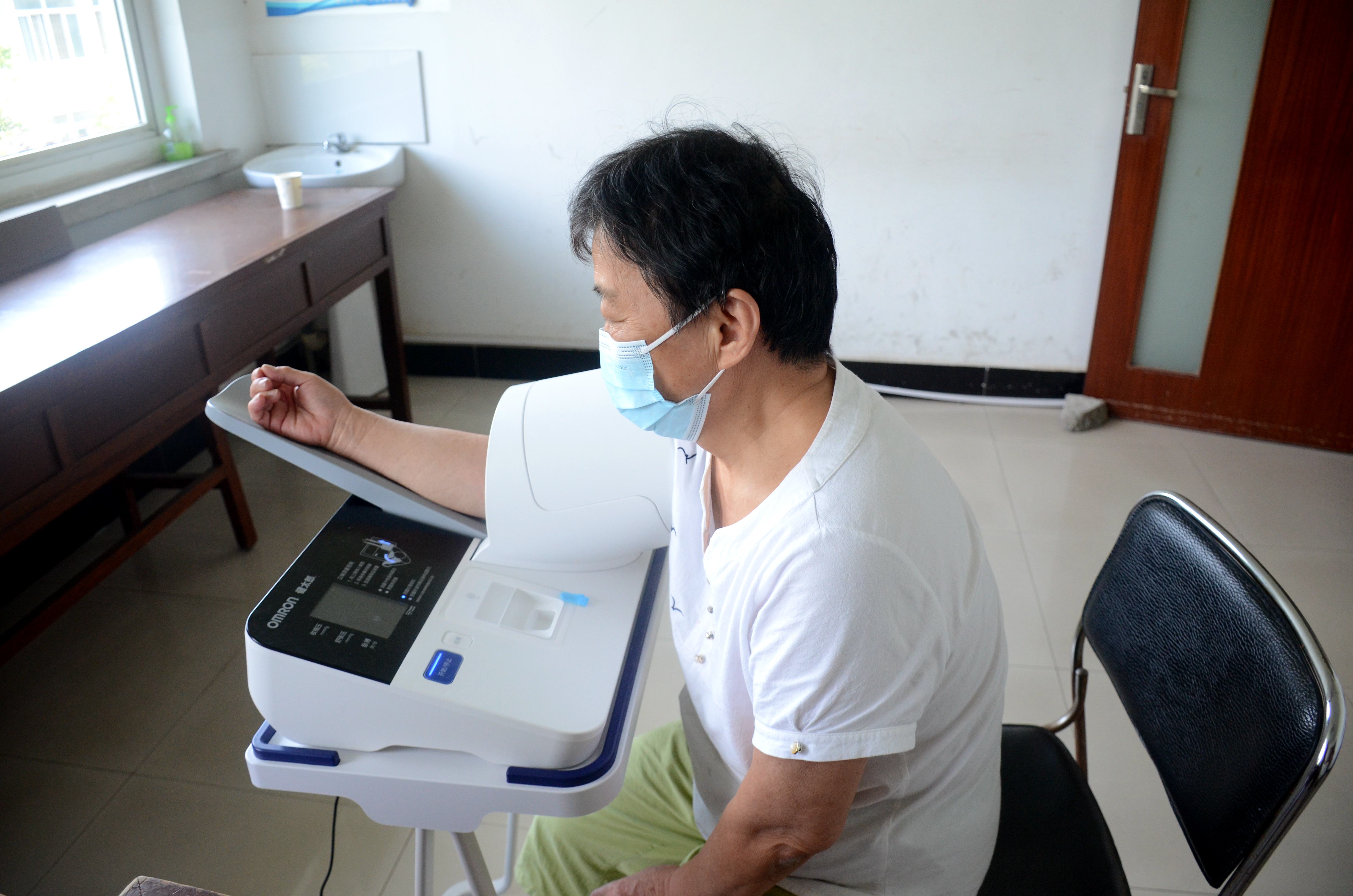 一名离退休教职工在自动测压仪上监测血压 （匡敏 摄）