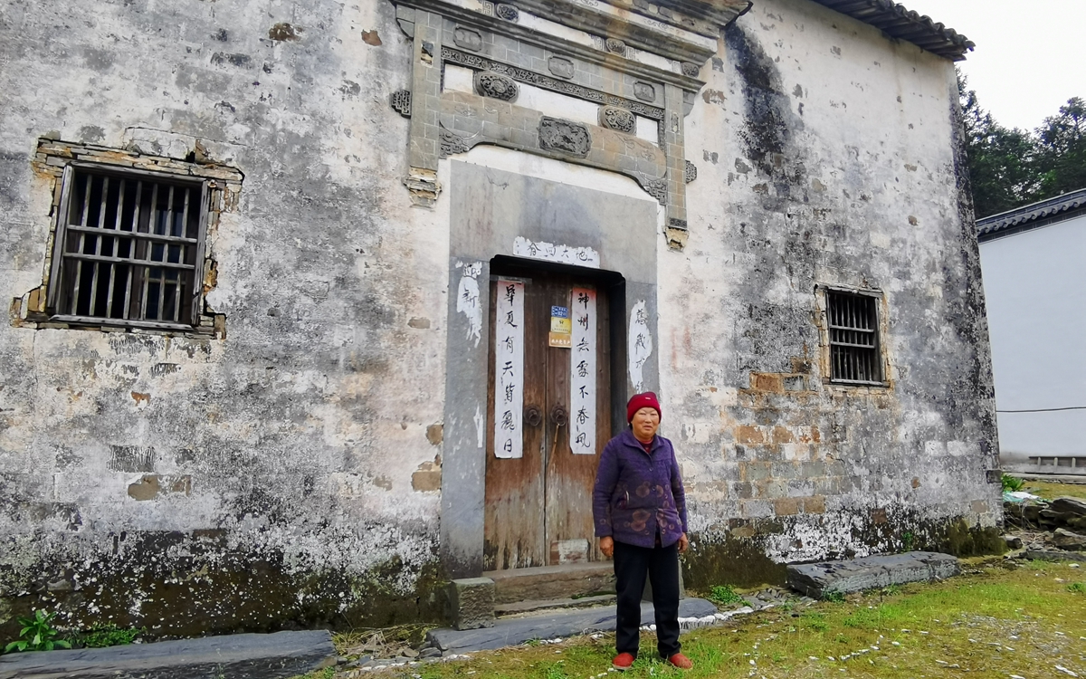 王文新站在自家老房子前。受访者供图