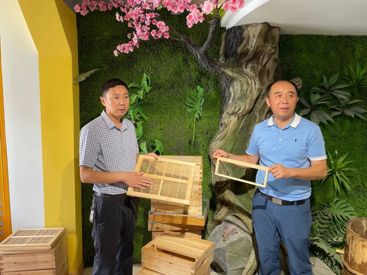 李翔（右）与望玲（左）向记者团介绍一种新型蜂箱