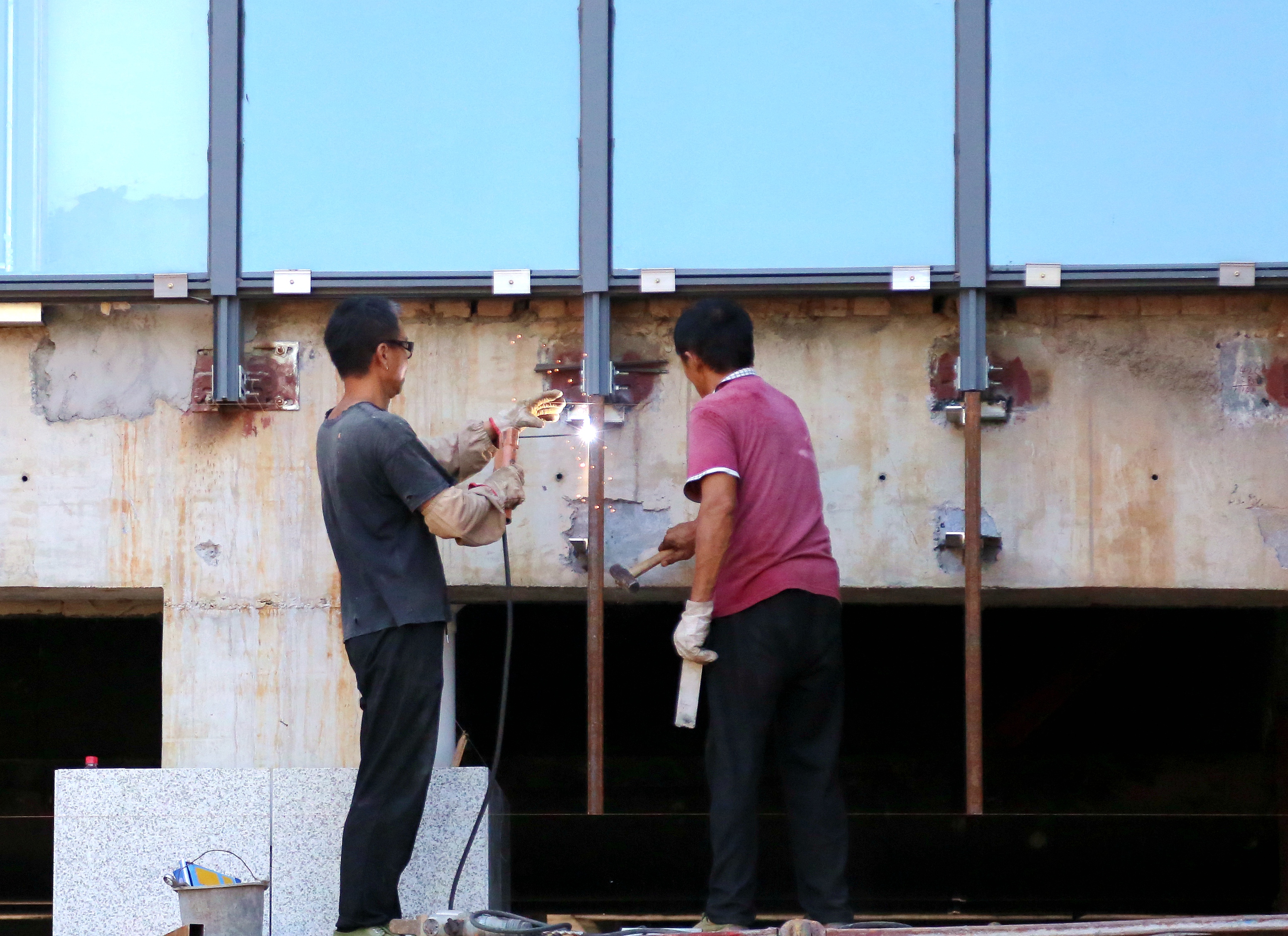 两位工作人员对新建的科研楼窗户进行焊接（匡敏 摄 )