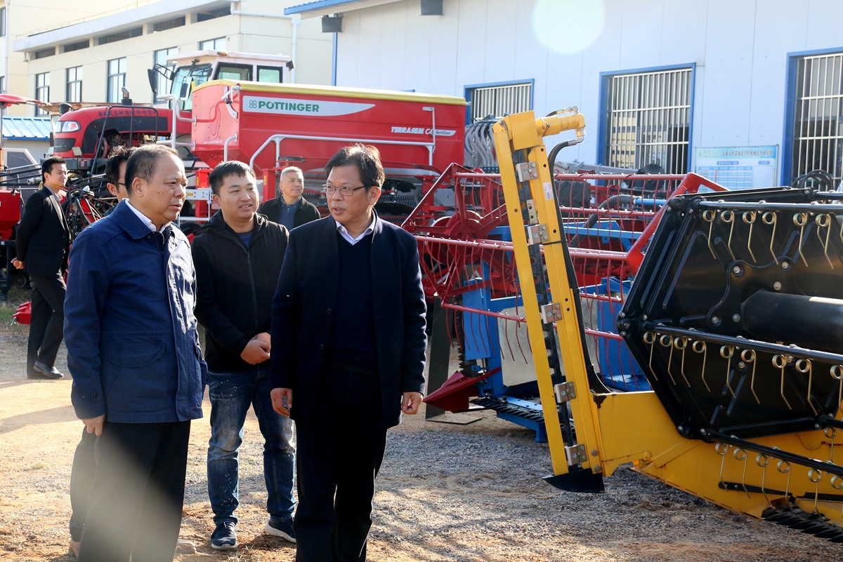 廖庆喜向副省长万勇（左一）汇报油菜全程机械化科研基地建设情况