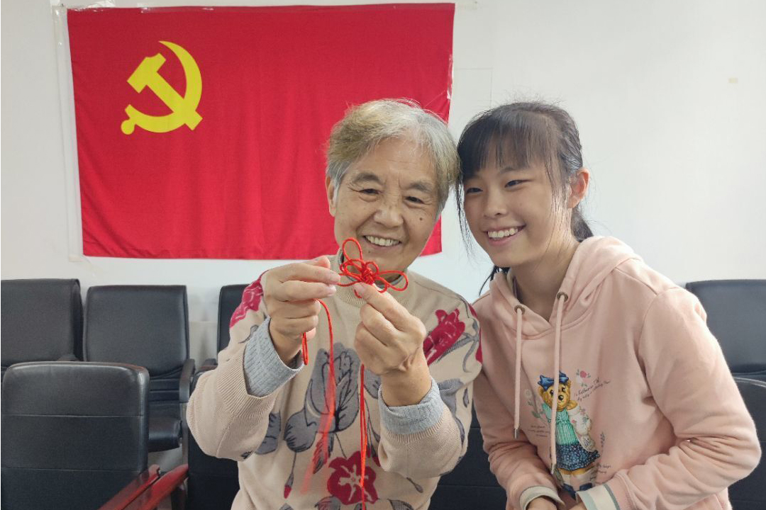 大学生志愿者与离退休教职工一起制作中国结（离退休工作部供图）