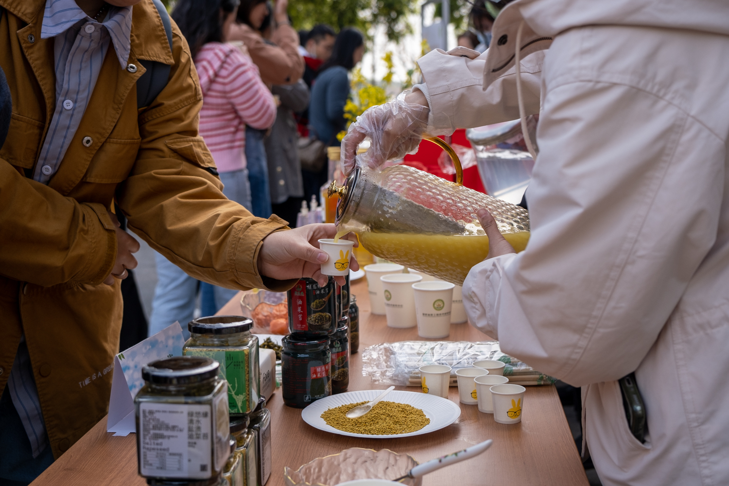 志愿者为活动参与者分发油菜花粉浆（学通社记者 周嘉键 摄）