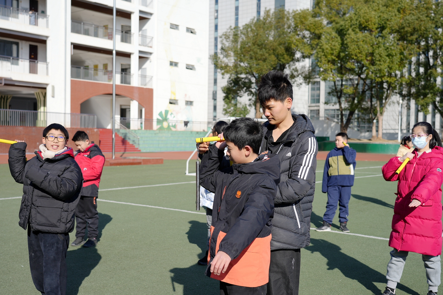 操场上，同学们在志愿者指导下学习如何玩转双节棍（记者 匡敏 摄）
