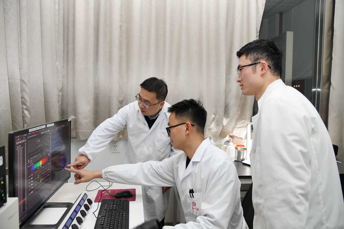 5 张飞教授（左）指导博士研究生王红星（右）、任杰用激光共聚焦显微镜观察报告基因的表达模式（记者 徐行 摄）
